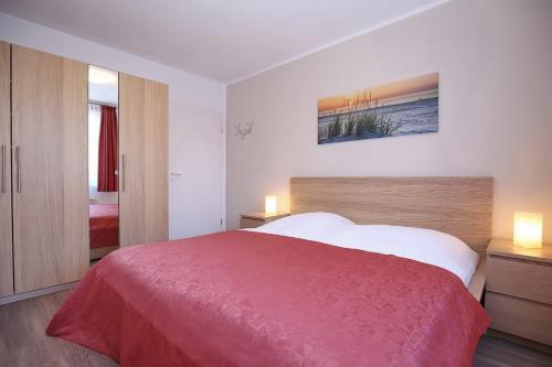 a bedroom with a large red bed with two lamps at Sünnslag Wohnung 029 in Boltenhagen