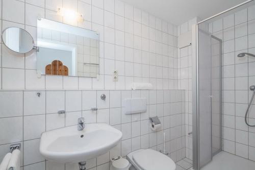 a white bathroom with a sink and a toilet at Dünenblick Wohnung 53 in Boltenhagen