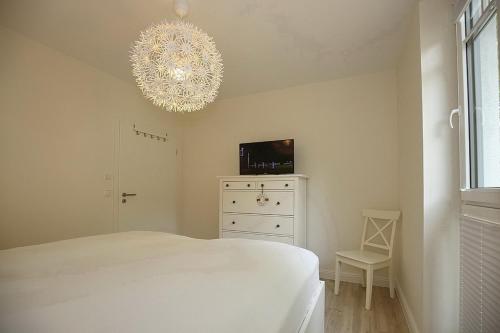 a bedroom with a white bed and a chandelier at Strandvilla Scholle - Hering Wohnung 03 in Boltenhagen