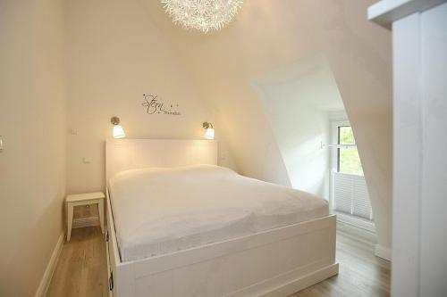 a white bed in a room with a chandelier at Strandvilla Scholle - Scholle Wohnung 05 in Boltenhagen
