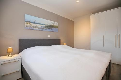a bedroom with a white bed and a white cabinet at Malaga Wohnung 1 in Boltenhagen