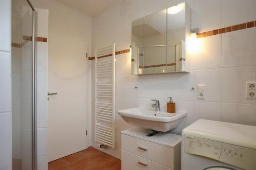 a white bathroom with a sink and a mirror at Malaga Wohnung 1 in Boltenhagen