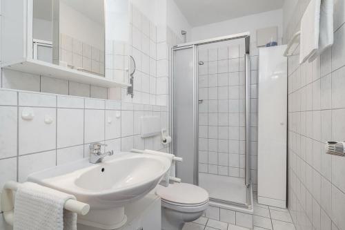 La salle de bains blanche est pourvue d'un lavabo et de toilettes. dans l'établissement Dünenblick Wohnung 33, à Boltenhagen