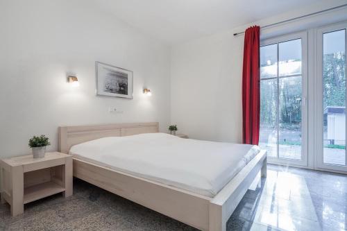 a white bedroom with a large bed and a window at Strandvilla Niklot Wohnung 02 in Boltenhagen