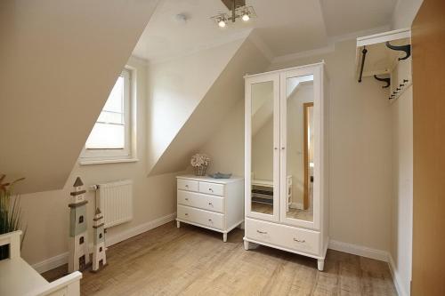 a attic bathroom with a dresser and a mirror at Strandvilla Krabbe Wohnung 10 in Boltenhagen