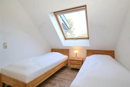 two beds in a small room with a window at Papillon Wohnung 16-7 in Boltenhagen