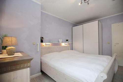 a white bedroom with a white bed and a desk at Goosbrink Wohnung 13 in Boltenhagen