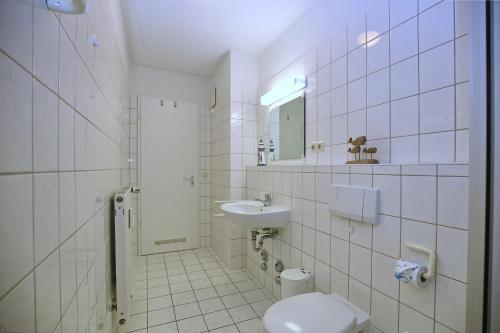 La salle de bains blanche est pourvue de toilettes et d'un lavabo. dans l'établissement Dünenblick Wohnung 34, à Boltenhagen