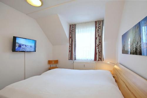 a bedroom with a white bed and a television at Haffblick Wohnung 11 in Boltenhagen