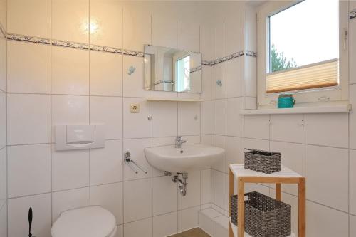 a bathroom with a sink and a toilet and a mirror at Strandvilla Krabbe Wohnung 03 in Boltenhagen