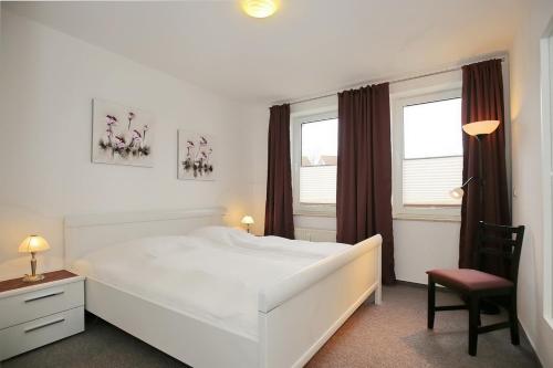 - une chambre avec un lit blanc, une chaise et des fenêtres dans l'établissement Sünnslag Wohnung 041, à Boltenhagen