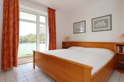 a bedroom with a bed and a large window at Haffblick Wohnung 25 in Boltenhagen