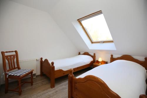 Cette chambre comprend deux lits, une fenêtre et une chaise. dans l'établissement Papillon Wohnung 01-6, à Boltenhagen