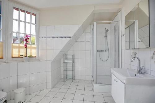 ein weißes Bad mit einer Dusche und einem Waschbecken in der Unterkunft Strandvilla Krabbe Wohnung 05 in Boltenhagen