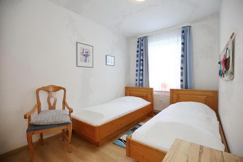 a room with two beds and a chair and a window at Dünenblick Wohnung 43 in Boltenhagen