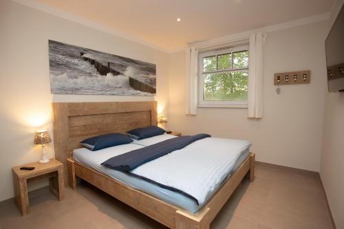 a bedroom with a bed and a painting on the wall at Reethaus Am Mariannenweg 11a in Boltenhagen