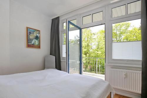 a bedroom with a white bed and a large window at Villa Triton Wohnung 04 in Boltenhagen