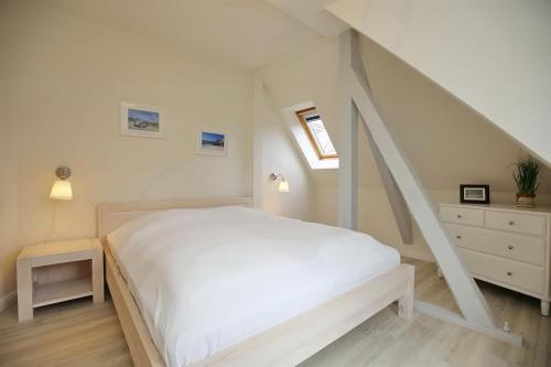 a white bedroom with a bed and a staircase at Villa Triton Wohnung 06 in Boltenhagen