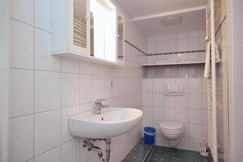 a white bathroom with a sink and a toilet at Villa Triton Souterrain Wohnung 07 in Boltenhagen