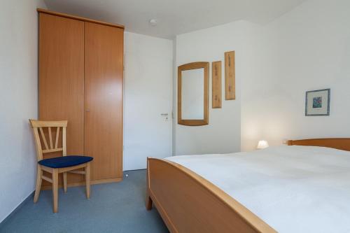 a bedroom with a bed and a chair and a cabinet at Dünenblick Wohnung 24 in Boltenhagen