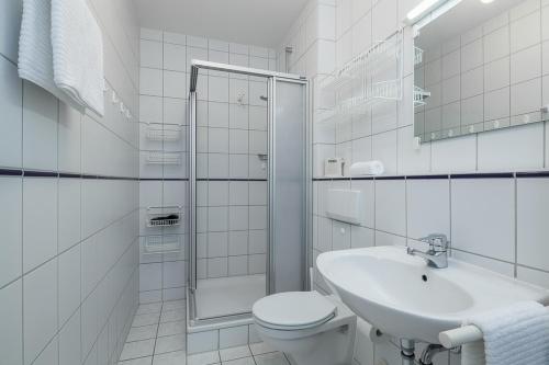 a white bathroom with a toilet and a sink at Dünenblick Wohnung 24 in Boltenhagen