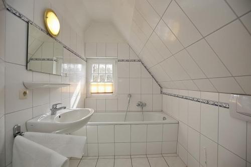 a white bathroom with a sink and a bath tub at Strandvilla Krabbe Wohnung 07 in Boltenhagen
