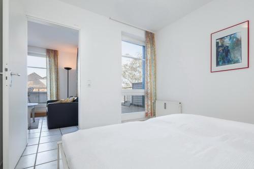 a bedroom with a white bed and a living room at Dünenblick Wohnung 50 in Boltenhagen