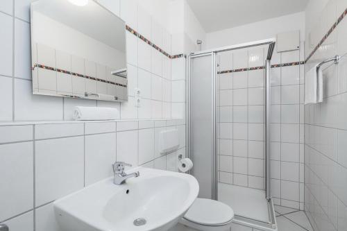 a white bathroom with a sink and a shower at Dünenblick Wohnung 50 in Boltenhagen