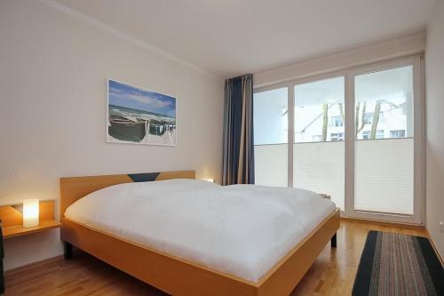 a bedroom with a large bed and a large window at Likedeeler Wohnung 15 in Boltenhagen