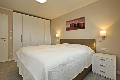 a bedroom with a large white bed and cabinets at Reethaus Am Mariannenweg 10a in Boltenhagen