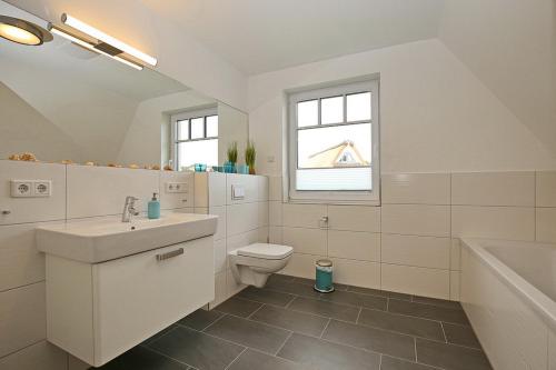 a bathroom with a sink and a toilet and a tub at Reethaus Am Mariannenweg 10a in Boltenhagen