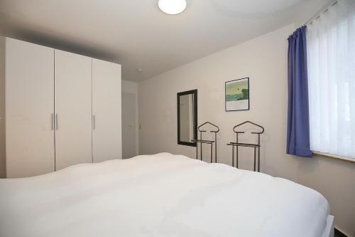 a bedroom with a white bed and blue curtains at Godewind Wohnung 27 in Boltenhagen