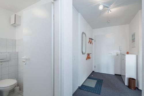 a white bathroom with a toilet and a sink at Godewind Wohnung 27 in Boltenhagen