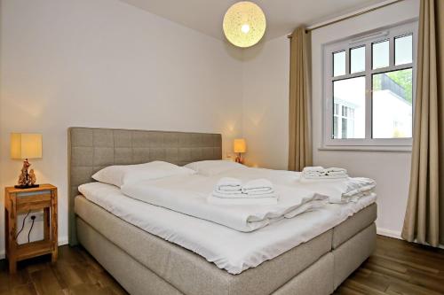 a bedroom with a large white bed with a window at Linden-Palais Wohnung 25 in Heiligendamm