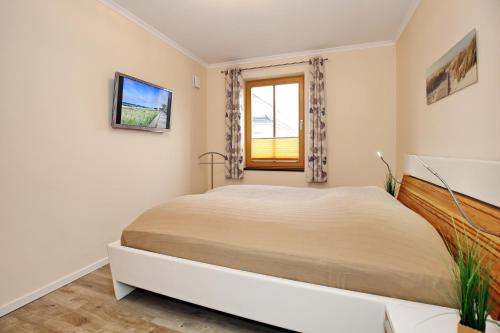 a bedroom with a large bed and a window at Villa Sanddorn Wohnung 07 in Börgerende-Rethwisch