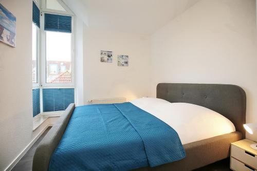 a bedroom with a large bed with a blue blanket at Sünnslag Wohnung 103 in Boltenhagen