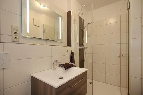 a bathroom with a sink and a shower with a mirror at Dünenblick Wohnung 10 in Boltenhagen