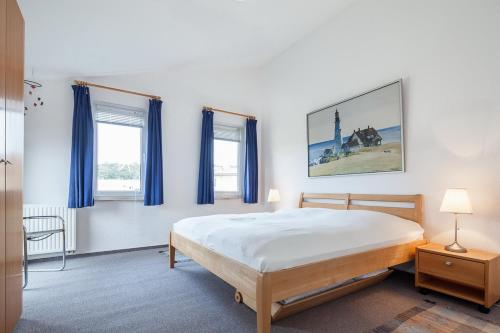 ein Schlafzimmer mit einem Bett und zwei Fenstern in der Unterkunft Godewind Wohnung 21 in Boltenhagen