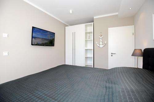 a bedroom with a bed and a tv on the wall at Haus am Wald Wohnung Meer in Wittenbeck