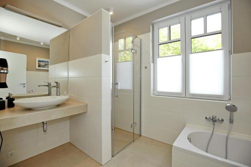 a bathroom with a sink and a shower and a tub at Haus am Wald Wohnung Meer in Wittenbeck