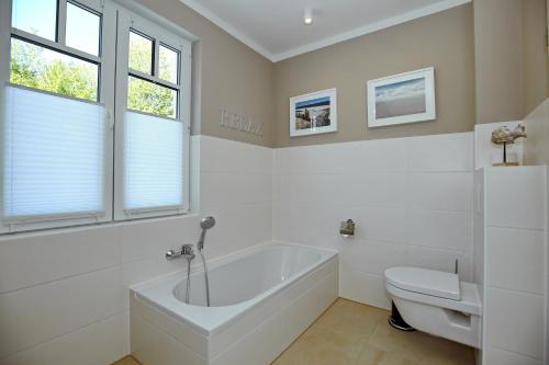 a white bathroom with a tub and a toilet at Haus am Wald Wohnung Meer in Wittenbeck