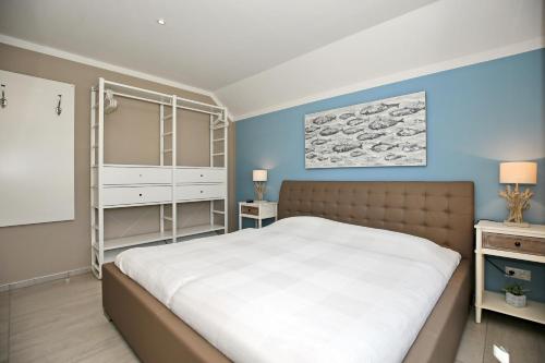 1 dormitorio con 1 cama blanca grande y paredes azules en Haus am Wald Wohnung Sonne en Wittenbeck