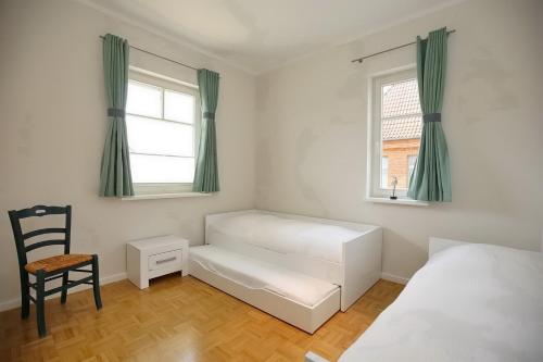 um quarto com uma cama, uma cadeira e uma janela em Likedeeler II Wohnung 02 em Boltenhagen