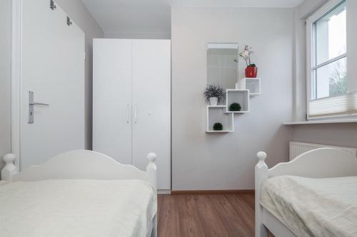 a white bedroom with two beds and a window at Papillon Wohnung 05-8 in Boltenhagen