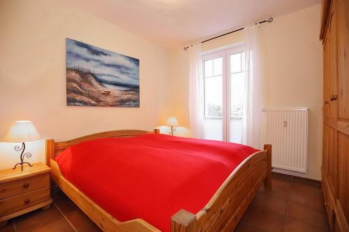 ein Schlafzimmer mit einem roten Bett und einem Fenster in der Unterkunft Achtern Diek Wohnung 18 in Boltenhagen