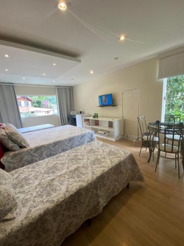 a bedroom with a bed and a table and chairs at Aconchego Serra Imperial - Suítes in Petrópolis
