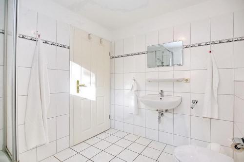 a white bathroom with a sink and a mirror at Strandvilla Krabbe Wohnung 01 in Boltenhagen