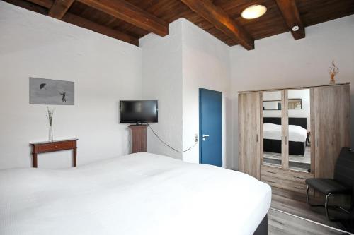 um quarto com uma cama branca e uma televisão em Auf den Höfen Wohnung 14 em Kühlungsborn