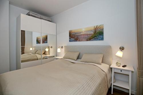 a white bedroom with a bed and a mirror at Meeresblick Wohnung 005 - 4 Sterne DTV in Kühlungsborn