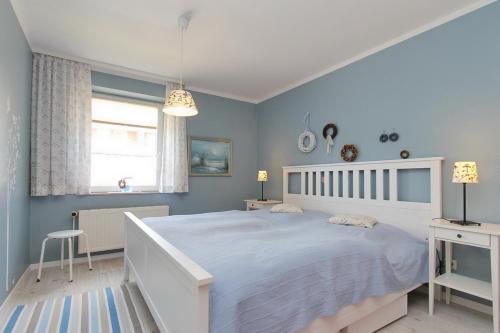 ein blaues Schlafzimmer mit einem weißen Bett und einem Fenster in der Unterkunft Goosbrink Wohnung 27 in Boltenhagen